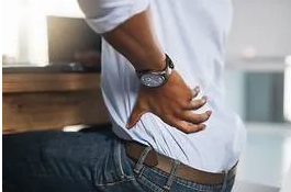 A man with his hands on the back of his lower abdomen.