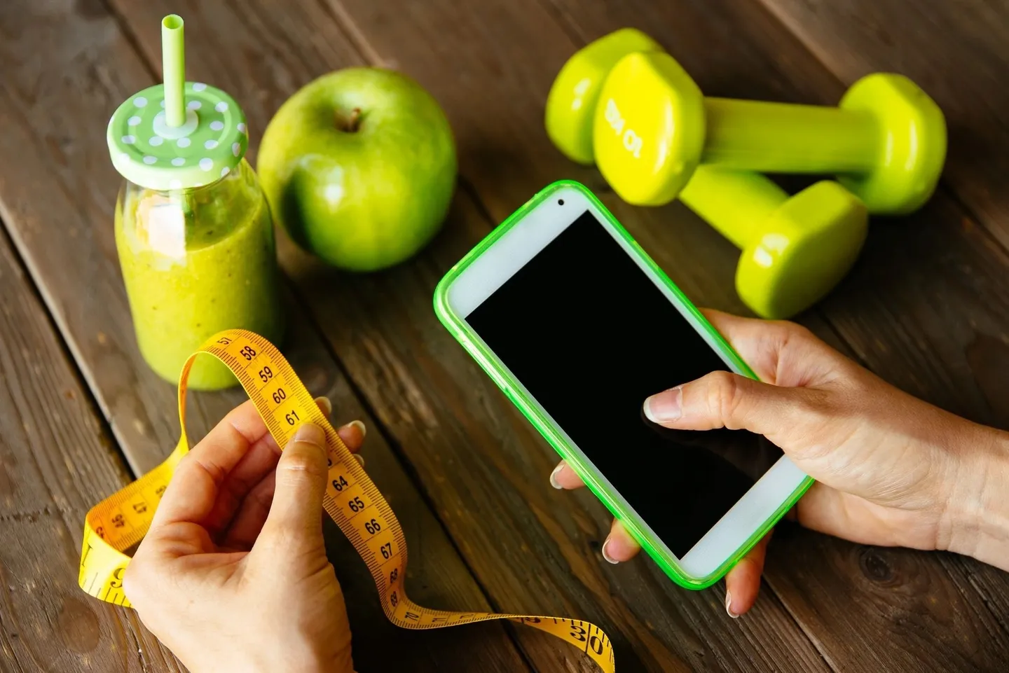 A person is holding a phone and measuring tape.