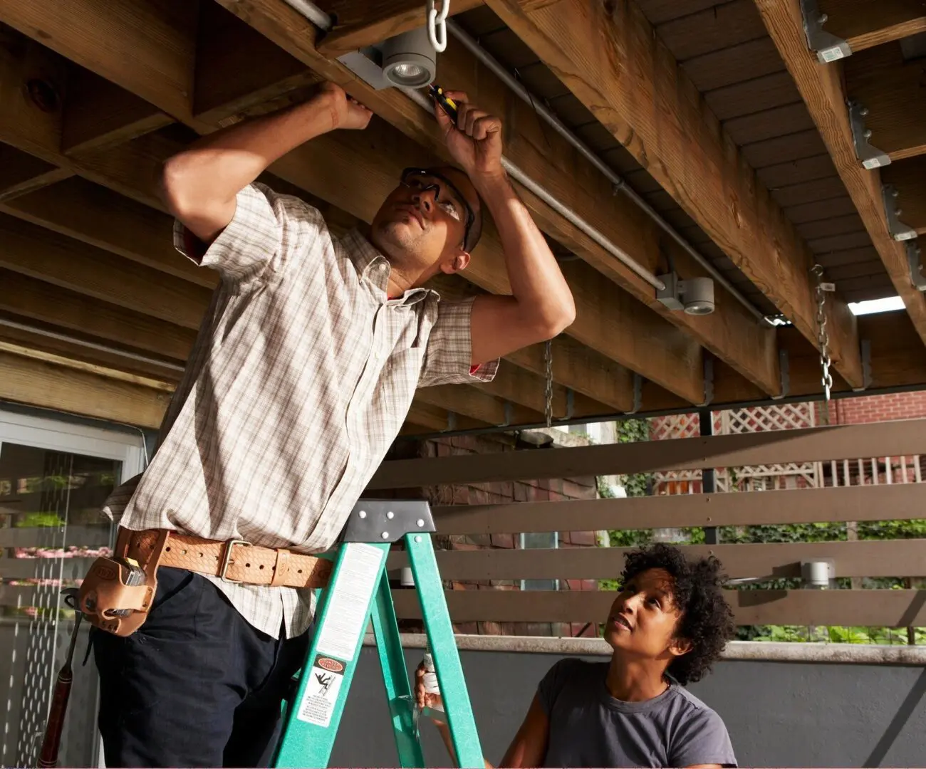 A man standing on a ladder and another person sitting down